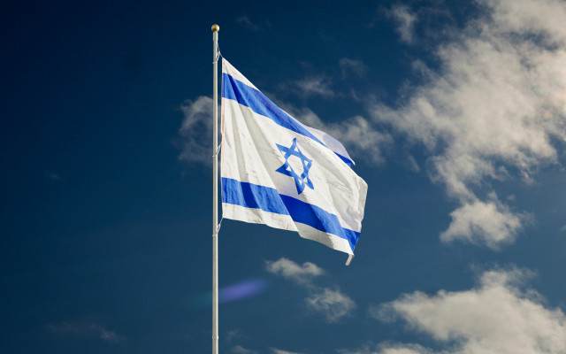 Zu sehen ist die israelische Flagge vor einem blauen Himmel mit weißen Wolken